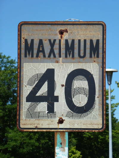 Canadian 40 km/h speed-limit sign with part of an earlier 25 mph marking visible beneath it